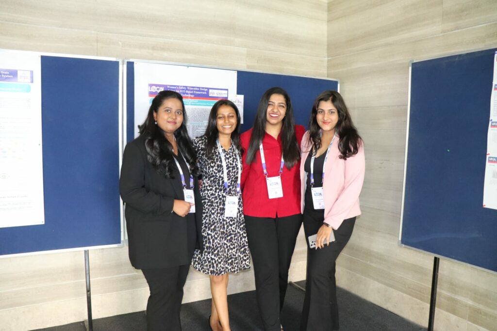 Four individuals at a conference standing in front of poster displays
